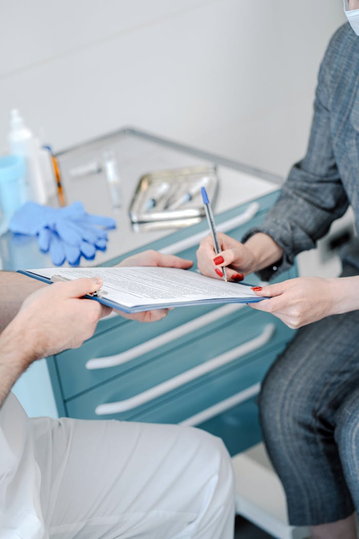 Patient signing healthcare agreement in doctors office, focus on hands and document exchange.
